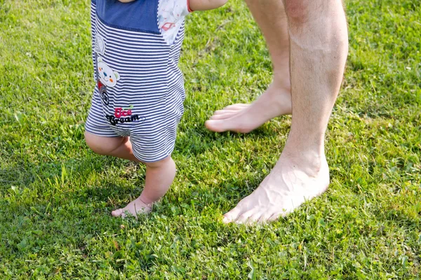 Padre e hijo pequeño. Primer plano de cómo el padre apoya al bebé cuando da los primeros pasos. manos masculinas sosteniendo las manos de un pequeño hijo. concepto de familia — Foto de Stock