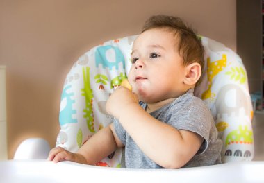 küçük mutlu bir çocuk yüzü bebek maması, bebek besleme aile, çocuk sağlığı kavramı nedeniyle zor bir sandalye ve yiyor çerezleri oturan yemek evde, komik ifade