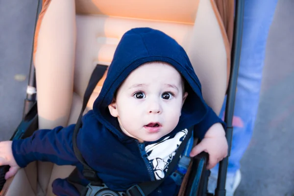 Small cute newborn baby boy sitting in a carriage in warm winter clothes with pacifier, concept of mothering autumn beanie, walk the in the Park, Close-up portrait — Stock Photo, Image