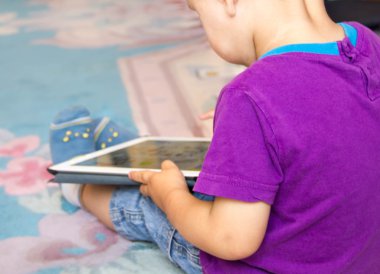 Erkek bebek tablet pc ile oynarken katta oturuyor. Yakın çekim fotoğraf el. Erken öğrenme küçük dokunmatik yüzey.
