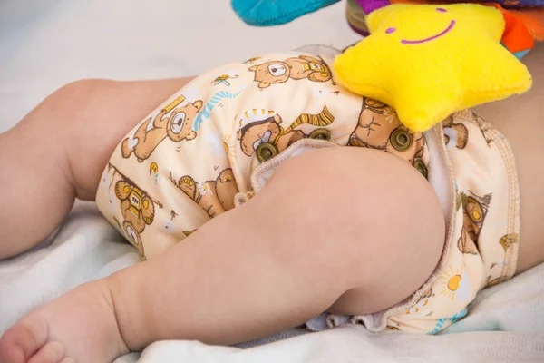 Baby in modern eco stacks of cloth diapers and replacement bushings selective focus close-up on bright background — Stock Photo, Image