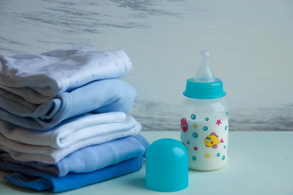 赤ちゃんの哺乳瓶と服のスタック — ストック写真