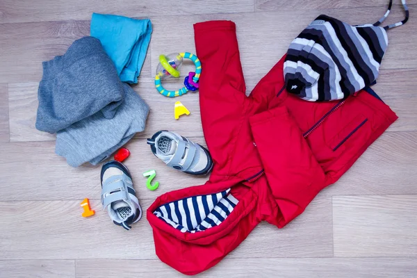 Ropa de invierno bebé, concepto, otoño, zapatillas de deporte, gorras, juguetes. cómo vestir al bebé en invierno. elegir los zapatos . — Foto de Stock