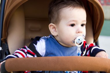 Sıcak kış aylarında bir arabada oturan küçük şirin yeni doğan bebek çocuk giyim ile emzik, sonbahar beanie annelik kavramı, yürümek Park, yakın çekim portre