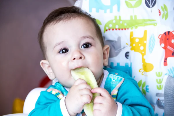 Baba eszik zöldséget. az etetőszék. fogzás, az uborka, a fogalom food, etetés. Újszülött otthon. egészséges. Az első gyermek enni tápláló snack. — Stock Fotó