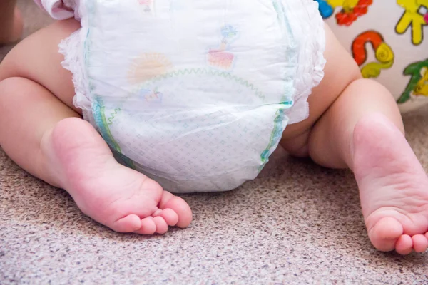 Baby in moderne wegwerpluiers met achterzicht, selectieve aandacht close-up op lichte achtergrond, kleine schattige voet jongen, het concept van gezondheid. hygiëne van het kind. — Stockfoto
