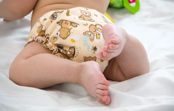 Baby in modern eco stacks of cloth diapers and replacement bushings selective focus close-up on bright background, little cute foot kid, the concept of health. hygiene of the child. reusable diapers — Stock Photo, Image
