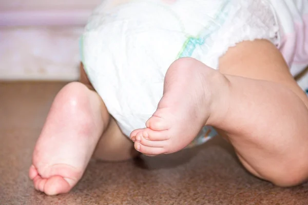 Bebé en pañales desechables modernos, vista trasera, enfoque selectivo primer plano sobre fondo brillante, pequeño niño lindo pie, el concepto de salud. higiene del niño . —  Fotos de Stock