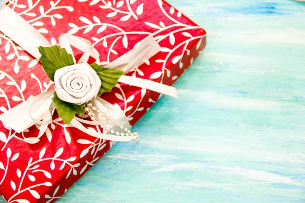 Tarjeta de Navidad caja de regalo roja con cinta de plata. fiesta invitación evento corporativo decoración mesa de madera de color turquesa shabby fondo. Vista superior, posición plana con mensaje de texto de eslogan de copyspace . — Foto de Stock