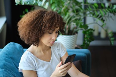 İnsanlar, teknoloji ve eğlence kavramı. Mutlu Afrika kökenli Amerikalı genç bir kadının evinde akıllı telefondan mesaj atması.