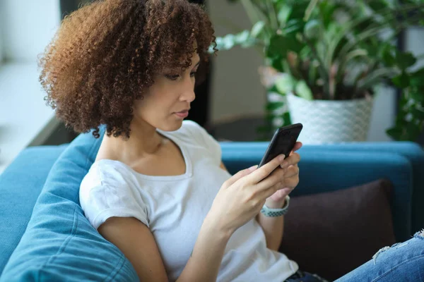 Persone, tecnologia e concetto di svago primo piano di felice afro-americano giovane donna sms su smartphone a casa — Foto Stock