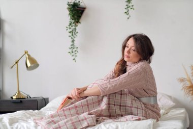 Sabah, rahatlık, Noel, kış ve insanlar konsepti - evde yatak odasında bir fincan kahve ya da çayla mutlu genç kadın