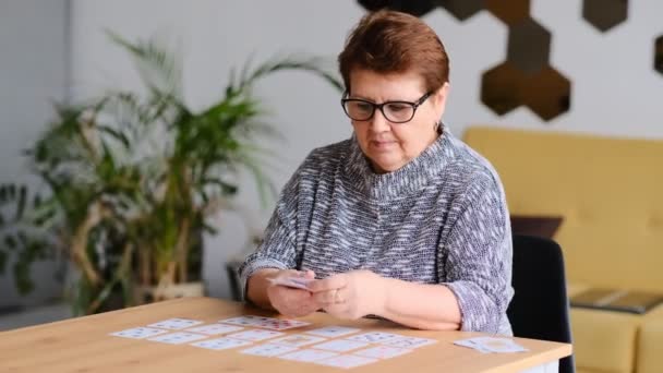 Seniorenvrouw die thuis solitaire speelt. gelukkig oud dame speelt een intellectueel spel close-up shot video. — Stockvideo