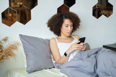 Gülümseyen Afrikalı Amerikalı kadın cep telefonu kullanıyor.