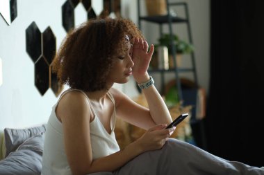 Gülümseyen Afrikalı Amerikalı kadın cep telefonu kullanıyor.