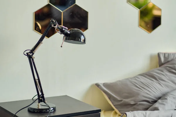 Lamp en boeken op een bijzettafel naast bed met kleurrijk beddengoed — Stockfoto