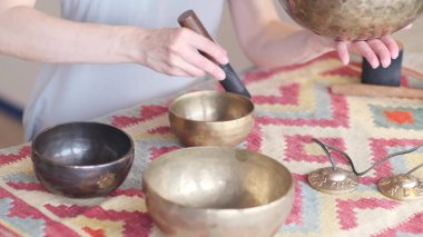 Kadın yoga minderinde otururken Tibet şarkı kasesinde oynuyor. Klasik tonlama.