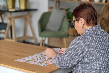 Son sınıf öğrencisi evde solitaire oynuyor. Mutlu yaşlı kadın entelektüel bir oyun oynuyor.