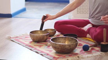 Kadın yoga minderinde otururken Tibet şarkı kasesinde oynuyor. Klasik tonlama.