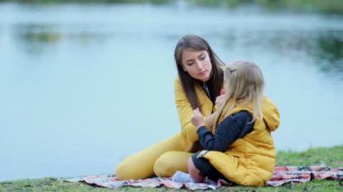Anne ve kızı sabun köpüklerini şişirir. Arka planda aile fotoğrafı. Sonbahar parkı, birlikte zaman geçirmek. Aile zamanı. Yakın çekim videosu. Yavaş çekim görüntüleri