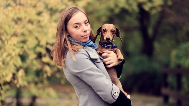 Genç bir kadın küçük köpeğine sarılıyor. Yaşam tarzı portresi. Kapat.