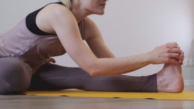 Evde yoga yapan güzel bir genç kadın. Yoga minderindeki asmalar. Antika tonlu. Yakın çekim videosu. Yavaş çekim.