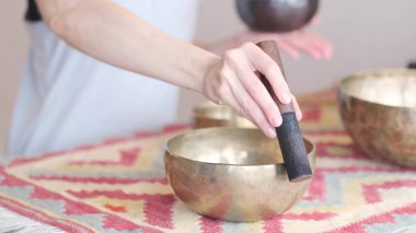 Kadın yoga minderinde otururken Tibet şarkı kasesinde oynuyor. Klasik tonlama.