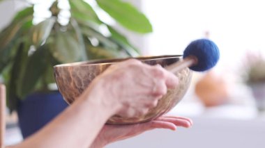 Kadın yoga minderinde otururken Tibet şarkı kasesinde oynuyor. Klasik tonlama.