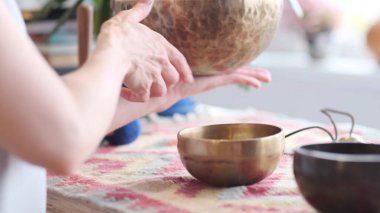Kadın yoga minderinde otururken Tibet şarkı kasesinde oynuyor. Klasik tonlama.