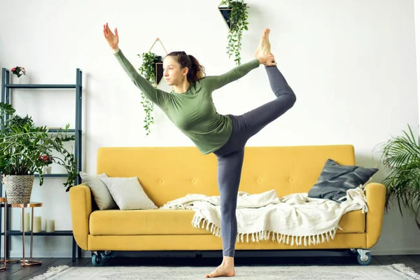Evde yoga yapan güzel bir genç kadın. Beden eğitimi çevrimiçi. — Stok fotoğraf