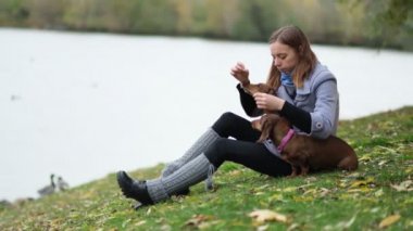 Gülümseyen bayan köpeğiyle boş zaman geçiriyor. Doğada küçük köpeğiyle rahatlayan bir kadın. Sırtını kaşıyorum. Köpek sahibinin burnunu yalıyor. Ağır çekimde kapat