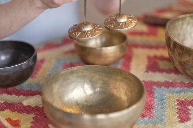 Kadın yoga minderinde otururken Tibet şarkı kasesinde oynuyor. Klasik tonlama.