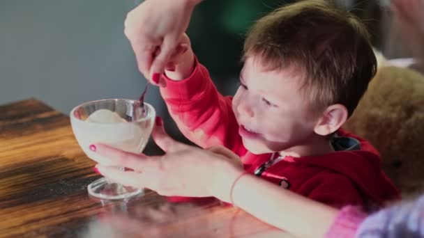 Mały chłopiec jedzący lody w kawiarni. Słodkie dziecko, delektujące się jogurtem waniliowym w restauracji. zwolnione ujęcie. — Wideo stockowe