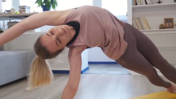 Evde yoga yapan güzel bir genç kadın. Yoga minderindeki asmalar. Antika tonlu. Yakın çekim videosu. Yavaş çekim. — Stok video