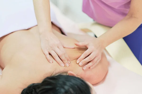 Fisioterapeuta Massagear as costas e ombros de uma paciente do sexo feminino. Sobre a visão do ombro do massagista realizando massagem profunda do tecido das mulheres de volta para liberar a dor — Fotografia de Stock