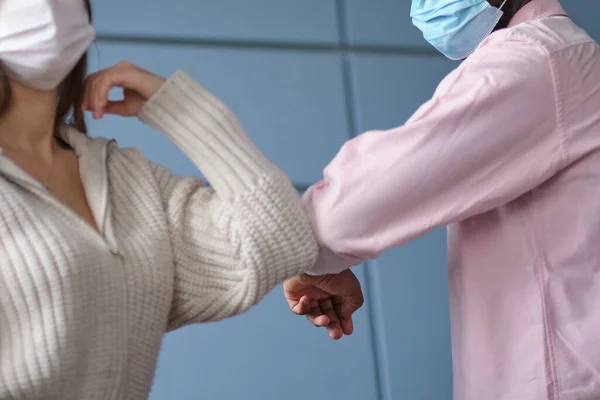 年轻的女商人戴着口罩，与非洲裔美国同事碰碰手肘，在大流行病后的办公室里进行无接触式问候。选择性重点 — 图库照片