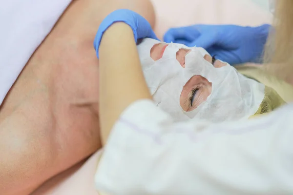 Ritratto ravvicinato di donna affascinante con gli occhi chiusi godendo procedura di cura della pelle. Braccia massaggiatrici che toccano mento e naso del cliente. Effetto anti-invecchiamento — Foto Stock