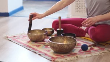 Kadın yoga minderinde otururken Tibet şarkı kasesinde oynuyor. Antika tonlu. Stok görüntüleri. Slow Motion videosu. Kapat.