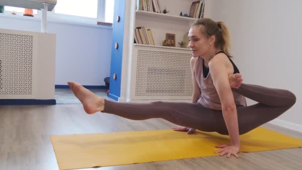 Mooie jonge vrouw die thuis yoga doet. asanas op yogamat. Vintage tonned. Sluit de video af. Langzame beweging. — Stockvideo