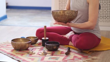 Kadın yoga minderinde otururken Tibet şarkı kasesinde oynuyor. Klasik tonlama.