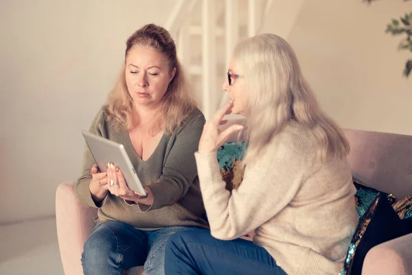 Mujer enseñando a la madre mayor a usar internet en casa. Mujer mayor con su hija mirando aparatos modernos en el interior. relajarse juntos, diferentes generaciones pasatiempo hobby. apoyo a las personas mayores — Foto de Stock