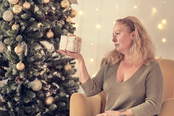 Sad woman by the christmas tree contemplating. Sad lonely woman complaining in christmas sitting on a couch in the living room at home. soft focus, warm tones