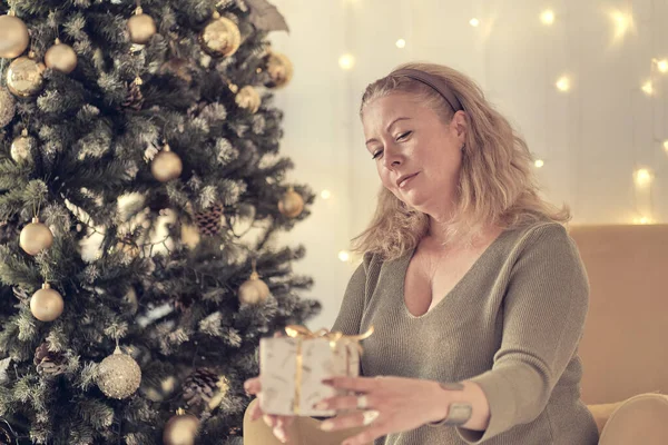 Sad woman by the christmas tree contemplating. Sad lonely woman complaining in christmas sitting on a couch in the living room at home. soft focus, warm tones