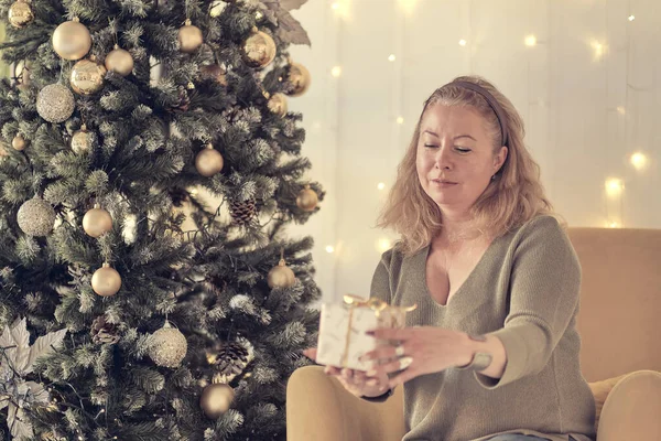 Sad woman by the christmas tree contemplating. Sad lonely woman complaining in christmas sitting on a couch in the living room at home. soft focus, warm tones