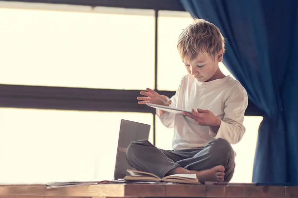 Geschäftsfrau mit Laptop und Sohn mit Tablet. Multitasking, Selbstständigkeit und Mutterschaftskonzept arbeiten zu Hause, während ihr süßer kleiner Junge neben ihr auf einem Tablet spielt, während sie arbeitet — Stockfoto