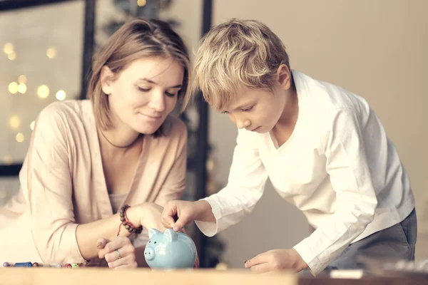 Μητέρα και παιδί βάζουν λεφτά στον κουμπαρά. Εκπαίδευση των παιδιών στον οικονομικό γραμματισμό. Χρήματα, μετρητά, επενδύσεις. — Φωτογραφία Αρχείου