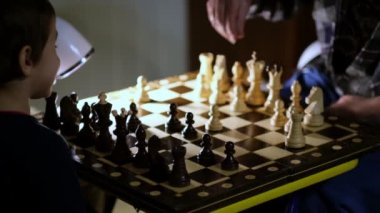 Büyükannesi evde torunuyla satranç oynuyor. Manzarayı kapat. Yavaş çekim. Çekilen video.