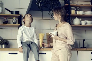 Genç anne ve oğul birbirlerine bakıyorlar. Sabah mutlu bir aile olacağız. Oğluyla birlikte mutfakta kahvaltı yapan güzel bir kadın. Oğlunun annesine bakıp gülümsemesi.