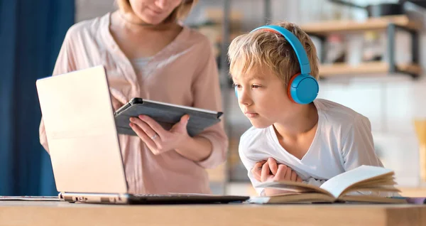 Mamá ayudando a su hijo pequeño con el ordenador portátil para hacer la tarea. Mujer joven enseñando a un niño a usar la computadora. niñera enseñando niña pequeña uso de la aplicación portátil. —  Fotos de Stock