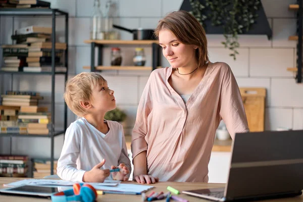 Fiatal anya kisgyerekkel, aki otthon dolgozik a számítógépen. multi tasking, szabadúszó és anyaság koncepció dolgozik otthon, mint az ő aranyos kisfiú játszik egy tabletta — Stock Fotó